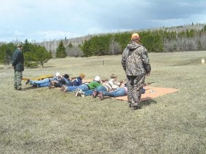 Bottom: Instructors Paul Eiler and Eric Nelms watch as firearm safety training participants practice what they learned.