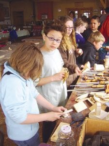 Above Left: (L-R) Daphne Lacina, Wellesley Howard-Larsen, Abby Prom, Sarah Gonzales, Chance Finke, and Connor Franks (leaning on the table) are sanding their canoes.