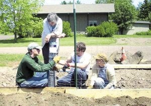 Above: Workers install a fence that will hopefully keep rabbits and deer from eating the delectable greenery that will be growing through the summer. Even those who will not have a spot in the community garden helped get it ready for its first year of local food production.