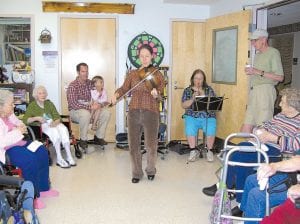 Photo by Nora Bockovich Musical nursing students! Two St. Scholastica medical students recently completed their clinical studies at Cook County North Shore Hospital and Care Center. Before leaving for the next stage of their training, they offered an impromptu concert at the Care Center. (L-R) Matthew Johnson, on spoons, with assistance from daughter Lucia; his friend and classmate, Laura Greensmith, fiddler and clogger; and Laura's mother Marge Smith on a tin whistle. Musical medical students