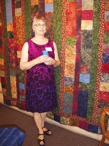 Leftt: Linda Chappell standing in front of her quilt at the June 26, 2009 opening of the Northwoods Fiber Guild show at Johnson Heritage Post. The quilt is made of many intricate batik fabrics, but she did not batik them herself, she said. That would have added a great deal of time to a project that already took a great deal of time! Right: This Voyageur hat and scarf made by Linda Bauer are part of the Northwoods Fiber Guild show that opened June 26, 2009 at Johnson Heritage Post.