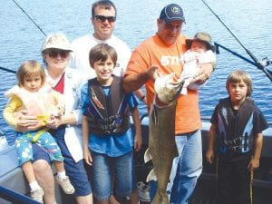 Captain Bear Atkinson and his dad, Niel Atkinson, show off the 17-pound lake trout caught on Clearwater Lake on July 4. The fish was brought in by Joe Matijasevich from Clearwater. The fish was hooked and was too beat up to let go. The trout was a great feast at the pontoon parade and celebration on Bearskin Lake. (L-R) Eva, Dixie, Mark, Joe Matijasevich, Niel and Bear Atkinson, Charlie Matijasevich.