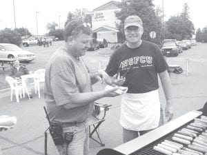 Several days of rain cleared in time for the annual North Shore Federal Credit Union customer appreciation picnic Wednesday, July 22, 2009. Credit union members enjoyed visiting with one another over brats and chocolate chip cookies. Steve DuChien (left) getting his brat from master griller Mark Summers (also the president of the Credit Union).