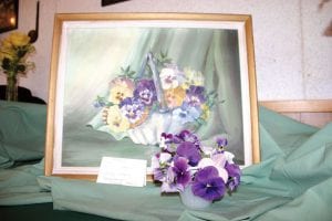 Above Left: Memories was the song brought to mind by this mirror image floral arrangement and painting. Ginny Storlie offered it in memory of Eleanor Annis, as did several other garden club members. Above: West End Garden Club members, dressed all in pink, were as lovely as their floral arrangements. (L-R) Jan Johnson, Flower Show Chair Gail Ring, Ginny Storlie, and next year's chair Katie Anderson. Left: This little lamb belonging to Carol Markwell was displayed with Lady's Mantle, Coral Bells, and Ivy to represent Oh, Mairzy Doats and Dozy Doats and Little Lambs Eat Ivy….