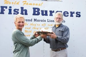 Staff photo/Rhonda Silence Since Grand Marais Mayor Sue Hakes was not available, Vice- Mayor Tim Kennedy had the honor of kicking off the 2009 Fisherman's Picnic by eating the first Fishburger! Diane Brostrom, director of the Grand Marais Area Tourism Association, presented the fishburger to Kennedy on a silver platter!