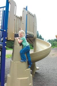 Photo by Sara Silence Above: Finally—kids got to play on the new playground, which features swings, bouncy horses, and an awesome circular slide, enjoyed by Kamryn Johnson, 3, Grand Marais.