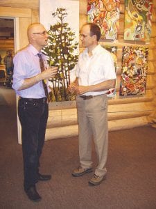 Staff photos/Jane Howard Left: Tim Young (left) talks with Braidy Powers at the opening of the Anne Cervenka/Tim Young exhibit July 31, 2009 at Johnson Heritage Post in Grand Marais. On the wall behind him hangs some of his artwork. Right: Jean Lindell (left) visiting with Anne Cervenka at the exhibit opening. Left: Young's work varies from passionate to whimsical. This series of dog paintings is definitely on the whimsical side. Below left: Cervenka's exhibit at Johnson Heritage Post includes numerous blown-glass vases in many vibrant colors.