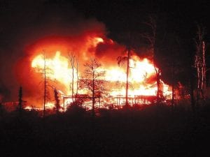 Photos by Dewey Pihlman By the time the Gunflint Trail Fire Department arrived on the scene, the Tony and Carol Feiock home was fully engulfed in flames. Right: Just a few days earlier, neighbor Dewey Pihlman took a photo of the reconstruction, overlooked by a rainbow.