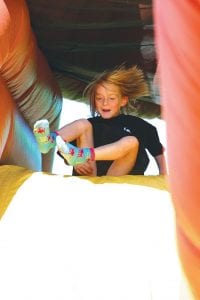 Staff photo/Laurie Johnson Annie Lynch, 6, tumbles down the giant inflatable dinosaur!