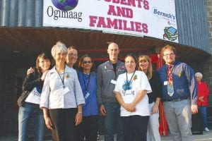 Staff photos/Rhonda Silence A delightful celebration was held on Monday, August 31 to dedicate Oshki Ogimaag (School of New Leaders) Charter School in Grand Portage. Upper left: The community got to meet the Oshki Ogimaag staff. (L-R) Bonita Poitra, Mary Bjorngjeld, Sherri Moe, Cecelia Vondall, Jeff Stork, Bridget LeGarde, Patty Foley, Keith Bergeron. (Not pictured Jacki Kozlowski, business manager; Jeanne Vogel, cook; Larry Deschampe, maintenance/bus driver; Heather Mantsch, IT). Above: Allan Aubid, Oshki Ogimaag school board vice-chair called all the students forward to cut the colorful ribbon, officially opening the new school!