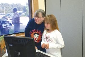 Upper middle: Madeline and Jasmine Rankin check out the new computers in the Oshki Ogimaag computer room. Above: Some of Grand Portage's new leaders—the Stonebridge Singers— offered a drum song. (L-R) Chase Gangler, Brent Sorenson, David Logan, John Pierre (partially hidden), Patrick Pierre, Kyler Deschampe.