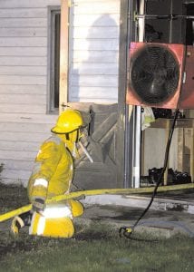 A Grand Marais firefighter ventilates smoke from the home of Tom and Stefanie Crosby at 406 First Avenue West, which was severely damaged by fire on Saturday, September 5, 2009.