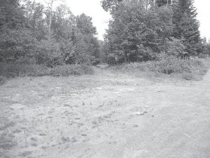 Before and after! Top: The land adjacent to the Lutsen Cemetery was not suitable for a cemetery before a generous donation of fill material and work by KGM Contractors. Above: Once the land was donated to the Lutsen Cemetery Association by George and Cindy Nelson and Scott Harrison, the site was cleared, fill material was brought in, and boulders were moved to terrace the land, which was seeded and mulched.