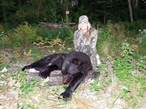 Right: Jennifer Abbott of Rosemount shot this male bear on Wednesday, September 2 near Grand Marais. Its dressed weight was 300 pounds. Upper left: A game camera set up by Mike Ficken Sr. took this photo of the same bear a few days earlier. Ficken helped Abbott with the hunt. He points out the white 