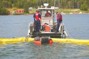 Staff photos/Andy Brostrom Above: The Canadian Coast Guard crew monitors the progress of the MI-30 skimmer as it cleans up a mock oil spill in the Grand Portage bay on September 16. Upper Right: Mark James, Canadian emergency response specialist, operated the vessel towing the 1,000-foot oil recovery boom. Right: The MI-30 skimmer is designed to recover 30 tons of oil per hour under perfect conditions. However, due to varying water conditions and other factors, it actually averages about six tons per hour.