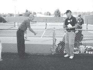 Staff photos/Jane Howard County Commissioner Jim Johnson cuts the ribbon at the grand opening of the new tennis courts west of Cook County High School Saturday, September 19, 2009. Standing to his right is Cook County Tennis Association member Mike Carlson. Gene Glader and Rod Wannebo are behind him.