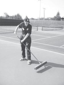 Rod Wannebo, Cook County Tennis Association vice president of administration and marketing, sweeps goose droppings from the new courts before demonstration play begins.