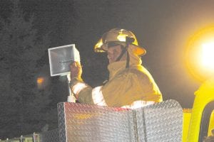 Staff photo/Rhonda Silence Maple Hill firefighter Doug Klein adjusts emergency lighting as the department worked to ensure that the fire at Pederson's home had burned out.