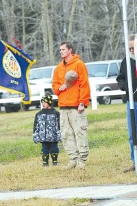 Army veteran William Owens and his son, Kadden, stand at attention as the National Anthem is played and the United States flag is raised. Kadden then helped his dad raise the flag honoring the members of the Merchant Marine.