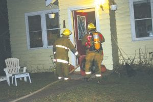 Grand Marais firefighters work to ventilate smoke from the home after the fire.