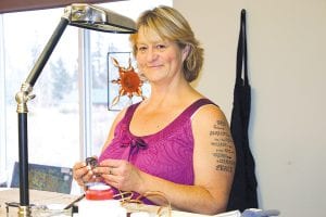 Katharine Peterson at her stained glass workshop at 1910 Highway 61 in Grand Marais. Her signature stained glass piece, which is her business logo, hangs in the window behind her at EpiphanyWorks.