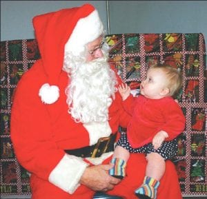 Staff photo/Rhonda Silence A new-old tradition at American Legion Post 413! The women of the Legion Auxiliary revived an old Legion tradition—a Children’s Christmas Carnival— on Sunday, December 20. In addition to a wonderful variety of carnival games, there was the requisite visit from Santa! Little Mercedes Michelle Johnson wasn’t sure what to think of St. Nick. See more Christmas carnival fun on page A14.