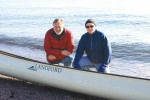 Top: Although canoe enthusiast Jack Stone (left) says canoes should touch only air and water, he was willing to bring a demo model of the luxurious Langford canoes he will be selling at Stone Harbor Wilderness Supply in Grand Marais. With him is Stone Harbor manager, Bryan Hansel. Right: Bryan Hansel makes a short portage to the Grand Marais East Bay. Above: Even the logo on the Langford wooden canoes is elegant.