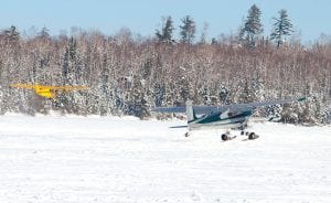 Unique winter transportation! Peter Schliep of Grand Marais in his yellow J3 Cub and Rob Nelson of Grand Marais in his home-built airplane enjoyed the winter scenery from the air and area lakes recently. The planes are pictured here taking off from Hungry Jack Lake.