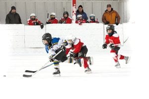 The Cook County Hockey Mites had a great time playing on the outdoor ice at the Woodland Glen Avon Tournament last weekend. Cook County players and coaches watch tensely from the box as Josh Prom (front) and Will Ramberg work on defense.