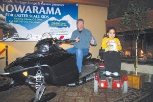 Easter Seals Ambassador Zachary Pylychuk celebrates with the Snowarama rider who won the Polaris 550 IQ Shift snowmobile, Gary Steele of Thunder Bay.