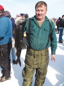 Left: The Cook County Ridge Riders Trout Derby on Sunday, February 28 on Gunflint Lake had a lot of happy ice fishermen, including Victor Pederson of Grand Marais with his prize-winning 10 pound 6 ounce lake trout. Below: Also enjoying the day was Jeanne Wilson of Grand Marais. Her son, Bradley, is holding the nice lake trout she caught.