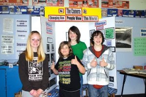 Left: Four Cook County Middle School students are heading to the University of Minnesota, Minneapolis on May 1 to compete in the state History Day competition. The students (L-R) Jessica Berg-Collman, Alex Jones (front), Megan Lehto, Joey Chmelik are standing standing in front of the award-winning display put together by Alex and Joey. Above: Alex Jones takes aim with a historic Brownie box camera, part of the history display he and Joey Chmelik submitted to regional competition.