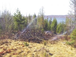 Sprinklers carrying water from Gunflint Lake were wetting down this patch of grass and brush several hours after it had burned beside a cabin on Gunflint Lake the morning of Friday, April 23, 2010. Bruce Kerfoot, owner of Gunflint Lodge about a mile away, said the Gunflint Trail Fire Department’s new 2,000-gallon pumper truck came in handy.