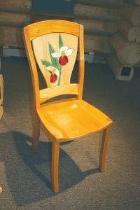 The Furniture Makers of Cook County exhibit will be at the Johnson Heritage Post until May 23. Don’t miss this wonderful woodworking show. Above: Stephan Holz has an elegant rocking chair in the exhibit, as well as this sturdy chair graced with a beautiful ladyslipper. Above right: One of the exhibit’s most unique pieces of furniture is this swinging camp chair made by Mark Hansen. Hovland watercolor artist Neil Sherman checks out this art he can sit on. Right: Simply beautiful is the only way to describe this unpretentious table and lamp duo made by David Prinsen.