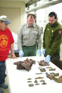 Grand Portage National Monument employees Karl Koster, Dave Cooper and Stephen Veit examine some of the artifacts found in the cribbing of the old dock that is now being replaced. The relics could be as early as the 1700s The three Grand Portage National Monument employees have been eagerly going through the 120 items (or more) found in the cribbing of the old dock.