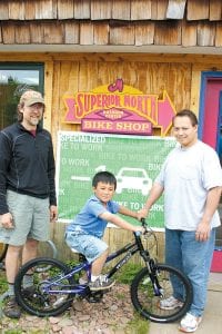 Above: Mark Spinler, Nathaniel and his dad, Joe Copeland, stand next to Nathaniel’s new bicycle. Nathaniel won it in the “Get Active Week