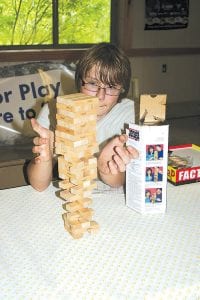 In case of rain, the club brought inside games, like Jenga. Above left: Jake Carlson plays the stacking game. It didn’t rain so club members were able to play lawn golf, horseshoes, and Giant Jenga. Above right: Breyer McQuatters pulls out the wrong piece and topples the Giant Jenga tower.