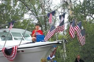 The rain fell before, during, and after the Tofte parade, but it didn’t stop the West End celebration. Jack Peck tossed candy from his dad Captain Darren Peck’s flag-bedecked boat.