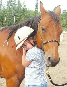 The Cook County 4-H horse program gives young people the opportunity to learn about horses, their care and beginning riding skills. Brenna Hay certainly enjoyed getting to know this gentle horse named Selena who belongs to Vicki Geretschlaeger.