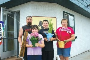 At the end of April, Clint and Sandi McQuatters family became the owners of Terra Bella Floral & Gifts in Grand Marais. Above: Family members all have their favorite flower or gift items. (L-R) Clint, Trace, Breyer, and Sandi. Left: Trace, 12, savors the scents of the flower shop.