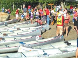 A crowd of canoes lines the shore as racers prepare to get underway.