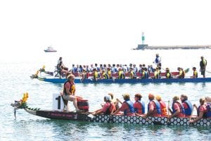 The Dragon Boats race across the harbor three at a time. In the calm before the drumming, teams talk strategy. The front boat is North House Folk School, the middle is overall winner A Better Dragon, and in back is the Heart of the Continent team.