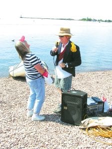 Top: “Admiral” Todd Miller entertained the boat watchers with jokes and bits of trivia. Above: Boats of all sorts floated past the Harbor Park beach, including several beautiful boats that were also seen at the Wooden Boat celebration.