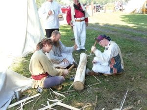 These voyageurs visit while they pound this black ash log to get strips for basket weaving. The rhythmic tap-tap-tap was heard throughout the voyageur camp. The workers are Jon MacKay of Fort Dodge, IA; Nathan Miller of Minneapolis; and Chris Pinkerton of Minneapolis.