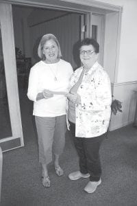 Katie Anderson (left) hands volunteer Sharron McCann a check to a local nonprofit organization that will benefit from the volunteer labor and profits this last year at First and Second Thrift Store in Grand Marais.