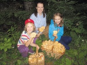 Above: Emma, Malin, and Linnea Åseby-Gesch look over the wonderful harvest of chantrelle mushrooms found near “an old logging road in Cook County.” The Åseby-Gesches found the mushroom patch while grouse hunting about five years ago. Right: Linnea holds another incredible find, coral mushrooms. Far right: Jason Gesch, a cook at Devil Track Landing, has an excellent grouse herb dumpling recipe with a delicious wild mushroom sauce.