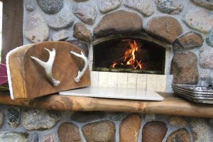 Sometimes it takes awhile to figure out that not all of the “old ways” of doing things were wrong. Nothing tastes better than bread baked on a wood-fired stove. Here Shevanise Harrison of Kingston, Jamaica tends to bread at Gunflint Lodge’s new outdoor oven. Built of stone by Gunflint Lodge owner Bruce Kerfoot, the oven is not only beautiful but produces great tasting bread. Shevanise is in her second summer as an intern at Gunflint Lodge.