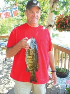 Left: Greg Gavel of Lindstrom, MN shows off the 20-inch smallmouth bass he caught in a Cook County lake recently.