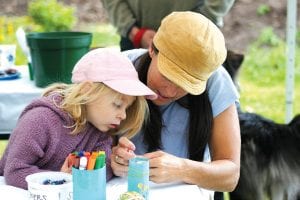 Patty Johnson and her daughter, Emma, make a beaded necklace in the kids’ tent on Saturday.