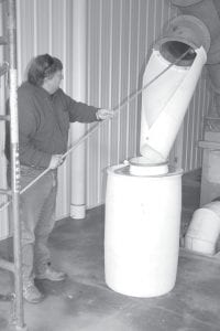 On September 22, 2010, Grand Marais Water/ Wastewater Superintendent Tom Nelson showed Public Utilities Commissioners the septic treatment plant built in Cedar Grove Business Park by Pete Gresczyk of G & G Septic Service. Septic waste is pumped from trucks into a processor where the septage is cleaned and sprayed and solids are separated from liquids. The resulting solids are fairly dry and do not smell bad or attract bugs, even in the summer, Nelson said. They are put into mesh bags that look similar to potato sacks and transported to a facility in Duluth. According to Nelson, solids from a truckload of septage don’t even fill up one bag. The liquids go into the city’s sewer treatment system under the ground. Processing the septage takes only 20-30 minutes. This facility will eliminate the county’s need for open septic dumping fields, which have been in short supply because of the terrain in Cook County. It will also eliminate a majority of the trips G & G Septic had been taking to dispose of septage in Duluth since the county has not had the needed septic fields in the last seven or eight years. “The standards are getting higher,” Nelson said. He told commissioners that leachate from the Taconite Harbor mining facility is discharged here and cleans out the underground tanks. Gresczyk pays more for what he sends into the city sewer system than city homeowners do because it is denser than what comes from houses. “Everybody won in this deal,” PUC Commission Hal Greenwood said. Right: Tom Nelson pulls treated solids into a transport bag.